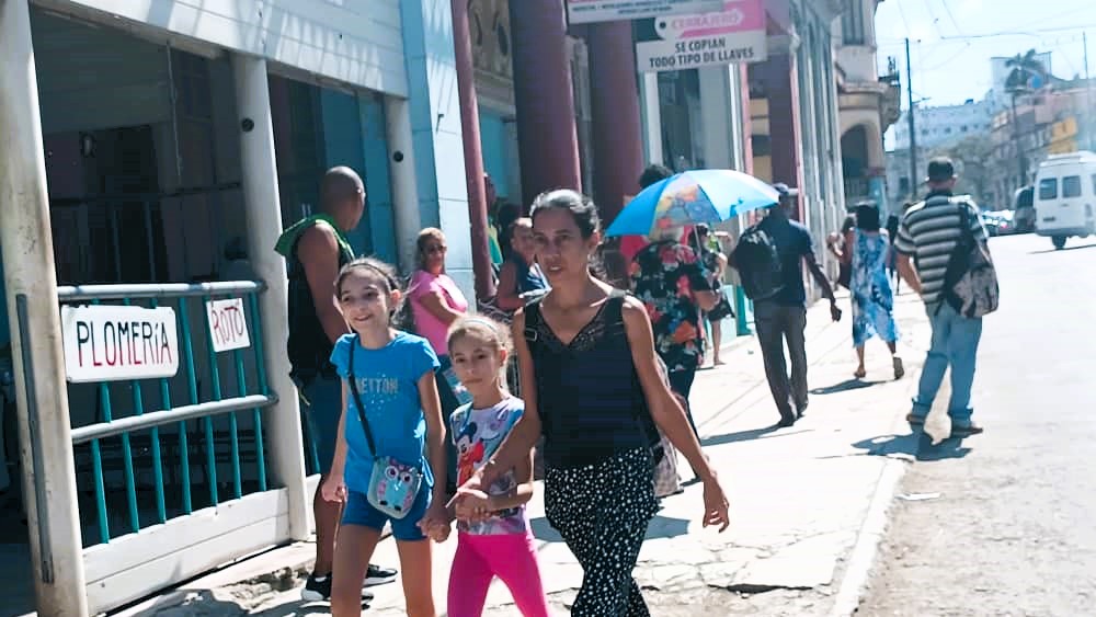 Una mujer y dos niñas caminan por una calle en Cuba.